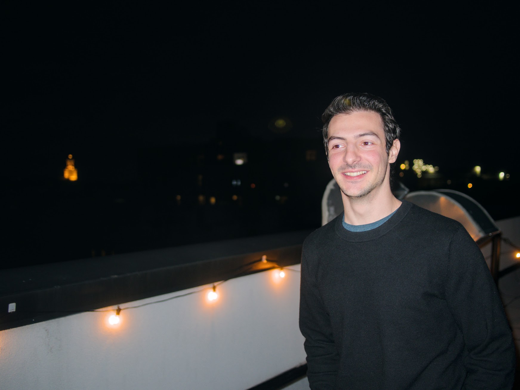 Daniel Pauker smiling on a rooftop at night